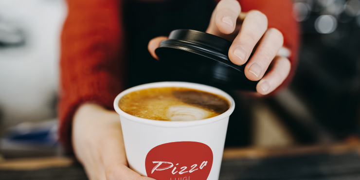 Person gibt schwarzen Deckel auf bedruckten Becher