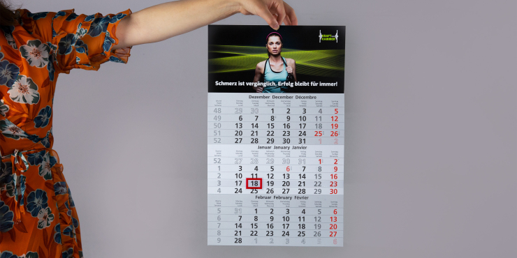 Jemand hält einen bedruckten Monatskalender