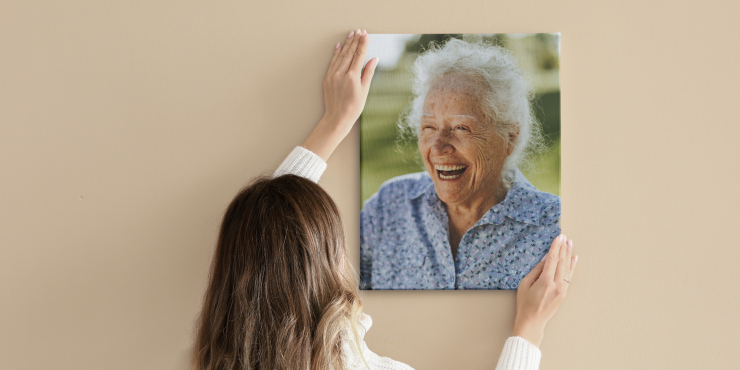 Frau hält bedruckten Keilrahmen an eine braune Wand