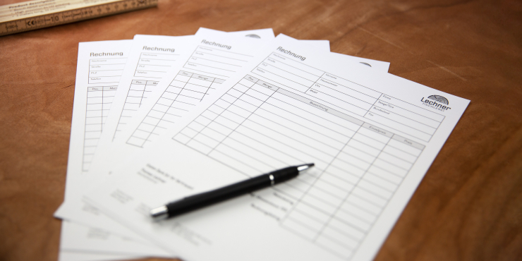 Durchschreibegarnituren liegen mit einem Stift auf einem Holztisch