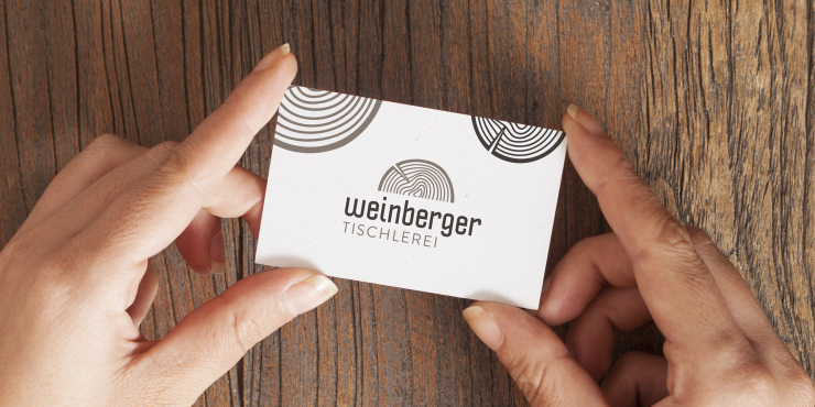 Zwei Hände halten eine Visitenkarte aus Recyclingkarton einseitig bedruckt