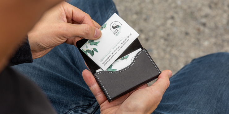 Person zieht Visitenkarte aus Lederetui für Visitenkarten