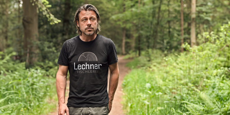 Mann mit kurzem T-Shirt einer Tischlerei im Wald