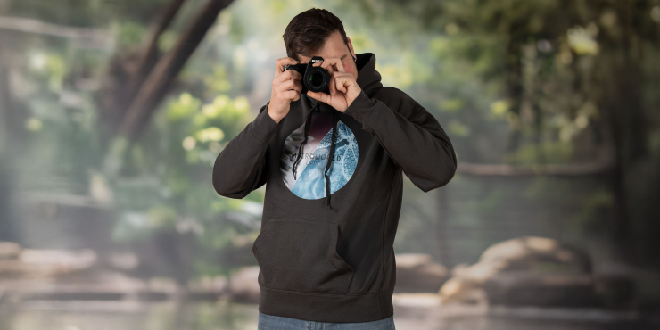 Mann fotografiert in der Natur und hat einen schwarzen Hoodie mit aufgedrucktem Motiv an