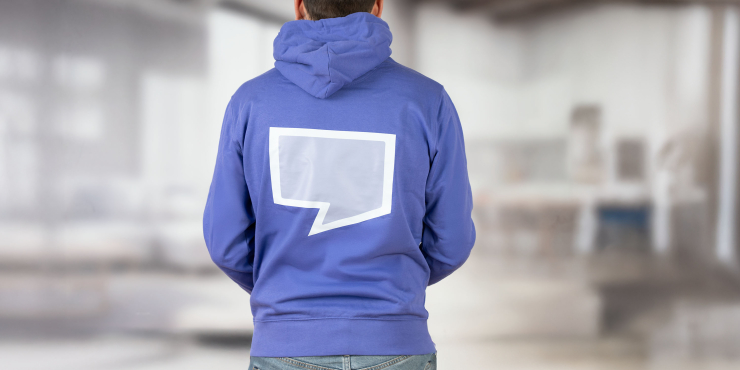 Mann im dunkelvioletten Cruiser Hoodie mit Aufdruck hinten steht im Raum