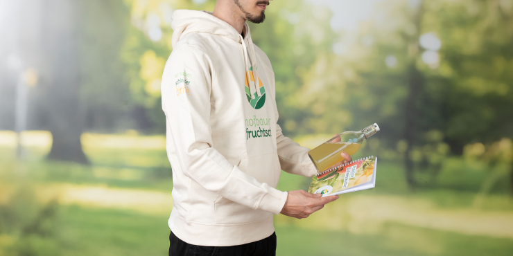 Mann steht im Garten und trägt weißen Stanley/Stella-Hoodie mit Aufdruck auf der Brust und am Ärmel