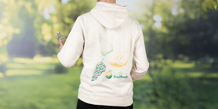 Mann steht im Garten und trägt weißen Stanley/Stella-Hoodie mit Aufdruck auf dem Rücken