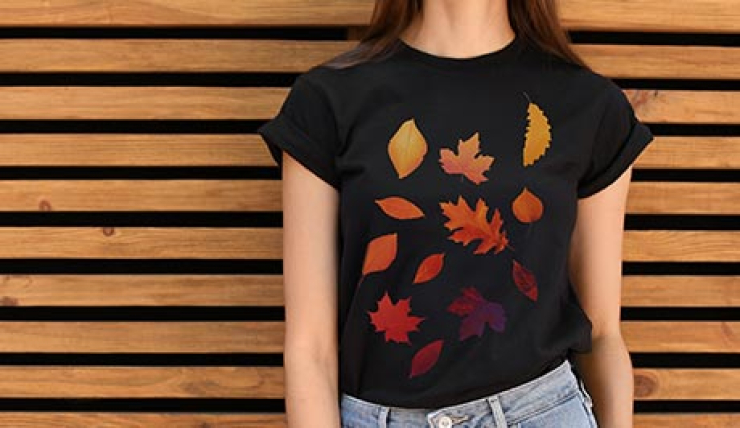 Frau steht mit schwarzen T-Shirt mit bedruckten Motiv vor einer Holzlamellen-Wand