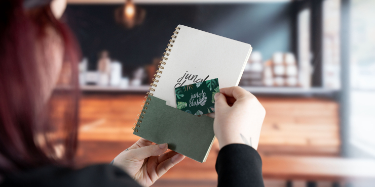 Eine Person steckt eine Visitenkarte in die Vordertasche des personalisierten A5-Hardcover-Notizbuch