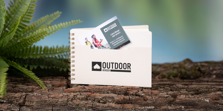 Personalisiertes A6-Notizbuch im Querformat mit Logo und Vordertasche zum Verstauen von Visitenkarten auf einem Baumstamm