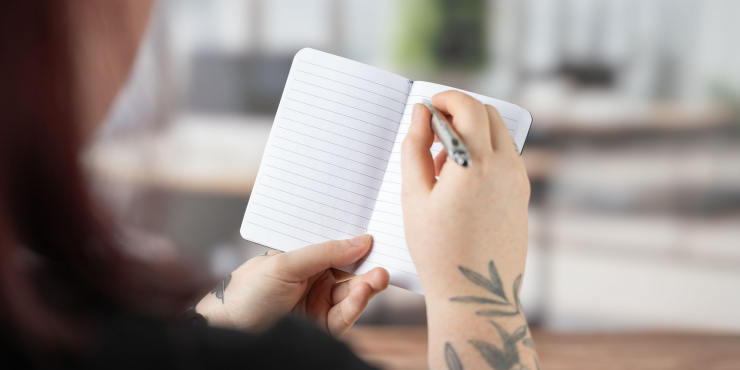 Person schreibt im offenen Molière A6-Notizbuch mit einem Kugelschreiber