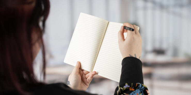 Person schreibt mit einem Kugelschreiber im personalisierten Cover Journal-Notizbuch