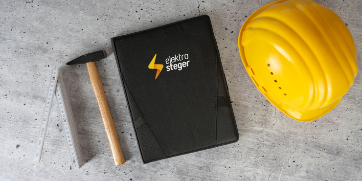 A4-Organizer mit personalisiertem Design liegt neben einem Zollstock, Hammer und einem gelben Baustellenhelm