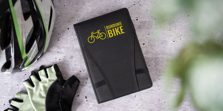 Nachfüllbarer A5-Organizer mit individuellem Design liegt neben einem Fahrradhelm und Fahrradhandschuhe 