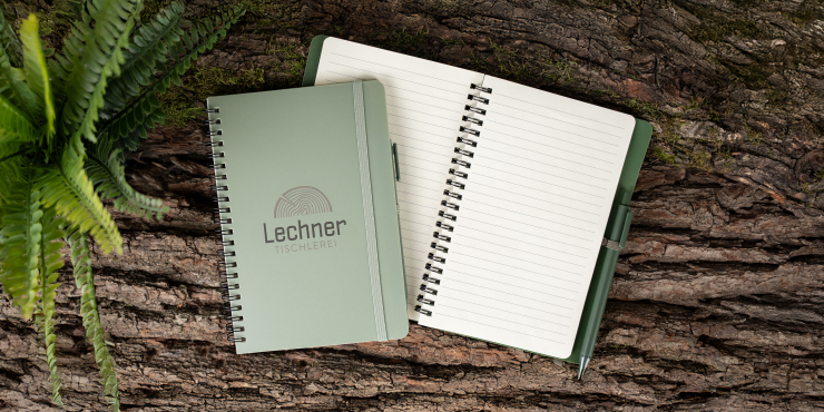 Geschlossenes und offenes Höga Repreve®-Notizbuch A5 mit eigenem Design auf einem Baumstamm
