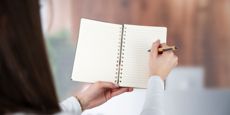 Person schreibt mit einem Kugelschreiber ins offene Terra Notizbuch