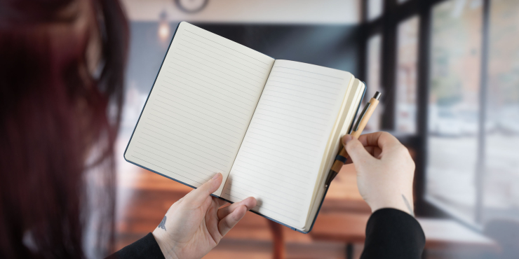 Eine Person nimmt gerade den Kugelschreiber aus der Stiftschlaufe des Terra Notizbuchs