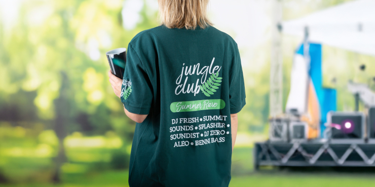 Frau trägt ein Poloshirt mit dem Aufdruck eines Festivals und befindet sich im Grünen