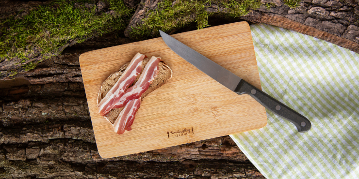 Frühstücksbrett aus Holz mit einem Speckbrot und Messer