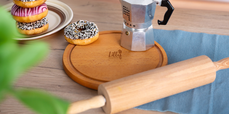 Diverse Backutensilien und Donuts liegen auf dem runden Schneidebrett mit Saftrille