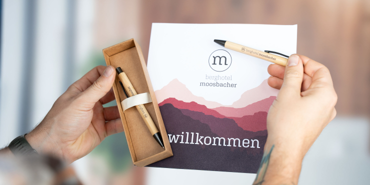 Person hält ein personalisiertes Schreibgerät vom Schreibset Bambowie in der Hand und schreibt auf einem Schild