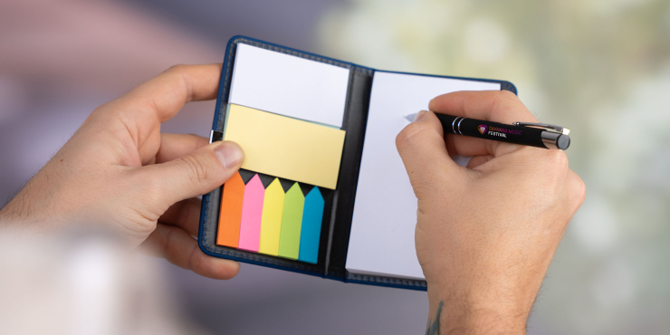 Person schreibt mit Kugelschreiber im Haftnotizbuch