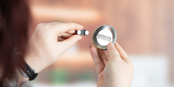 Person hält Kleidungsmagnet in der rechten Hand und zieht mit der linken Hand den Magneten weg