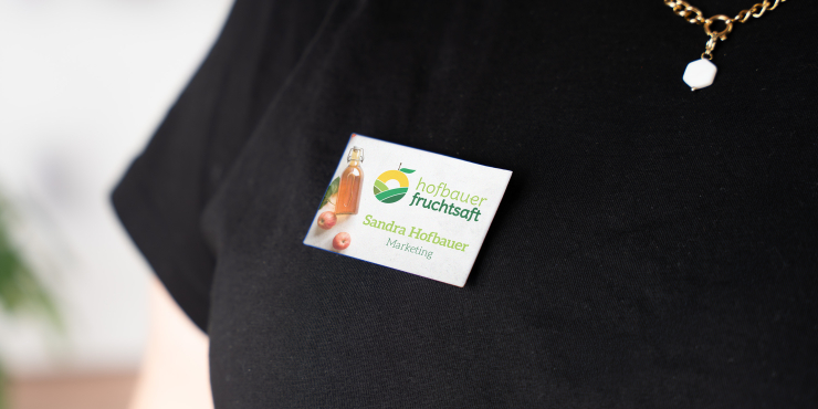 Rechteckiger Button mit Nadel und personalisiertem Design als Namensschild auf einem schwarzen T-Shirt