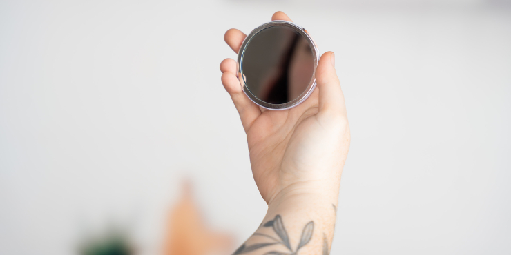 Person hält Button mit Spiegel in der Hand