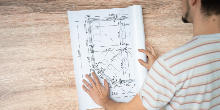 Laminierter CAD-Bauplan wird von einer Person aufgerollt