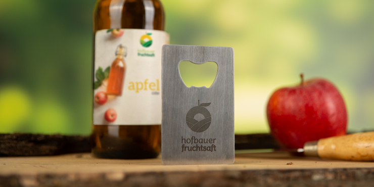 Bedruckter Edelstahl-Flaschenöffner vor einer Glasflasche