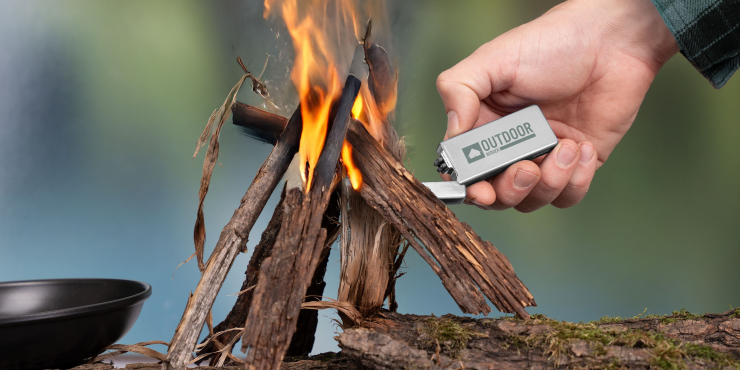 Person zündet ein Lagerfeuer mit einem bedruckten Formula Feuerzeug an