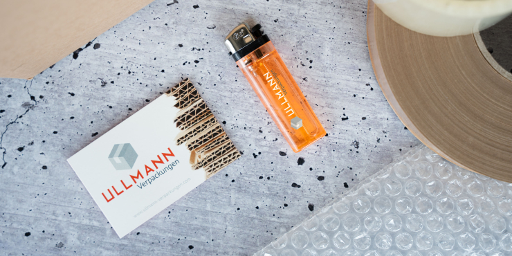 Transparentes Go Feuerzeug liegt auf Beton mit einer Visitenkarte