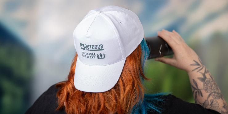 Eine Frau trägt eine individuell bedruckte Baseballkappe und trinkt aus einer Getränkedose