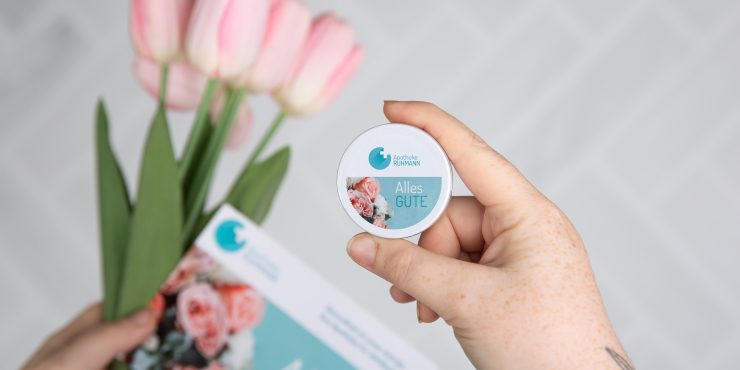 Frau hält XS-Taschendose mit personalisiertem Aufdruck in der Hand und hält einen Tulpenstrauß und eine Broschüre in der anderen Hand