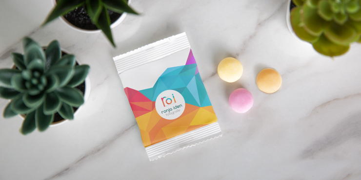 Individuell gestaltete Tüte mit buntem Design und drei Bonbons auf Marmoruntergrund