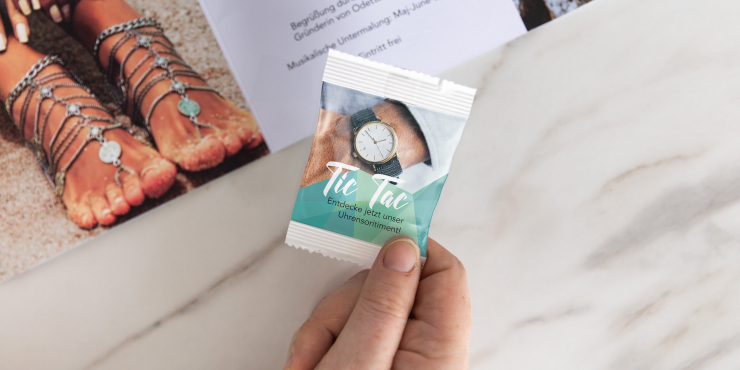 Individuell gestaltete TicTac Verpackung in Händen neben Schokoriegel