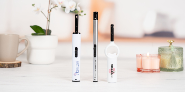 Stabfeuerzeuge mit individuellem Druck stehen auf einer weißen Fläche neben Kerzen