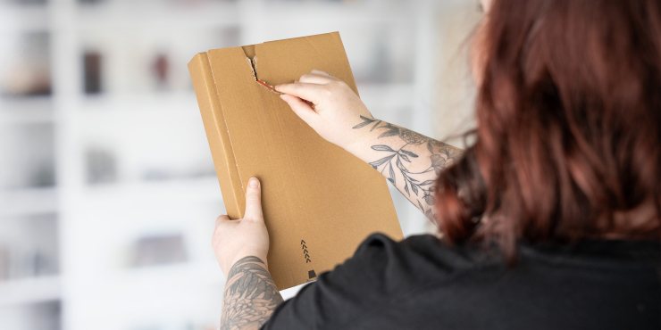 Eine Person hält und öffnet eine Versandtasche