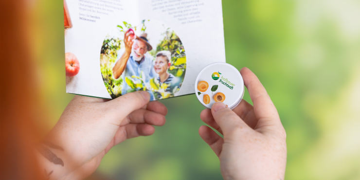 Individuell gestaltete XS-Taschendose in Hand und in anderen Hand eine Grußkarte