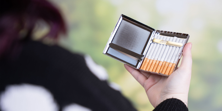 Metallenes Zigarettenetui mit den Zigaretten geöffnet in der Hand liegend