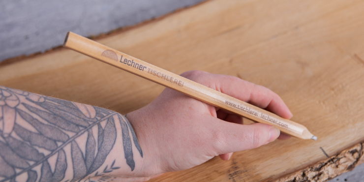 Person hält einen gravierten Zimmermannsbleistift und markiert ein Holzstück