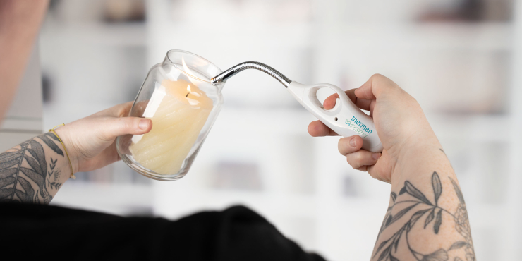 Person zündet eine Kerze im Glas mit dem ZORR Gasmatch Flexi Feuerzeug an