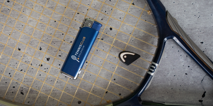 ZORR LED Feuerzeug mit individuellem Druck liegt auf einem Tennisschläger