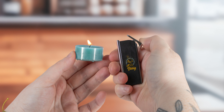 Person hält ein Feuerzeug und eine Kerze in einer Bar in den Händen
