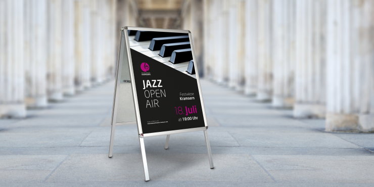 Kundenstopper mit individuell bedrucktem Plakat steht in einer Halle umgeben von Säulen