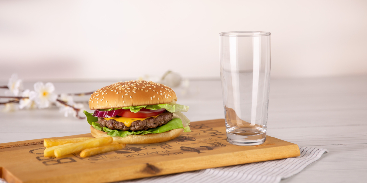 Bierglas auf einem Tisch mir Burger und Pommes