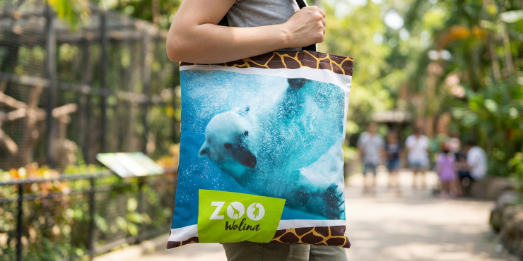 Person trägt kleine Tasche mit individuellem Motiv aus Displaystoff, während sie in einem Zoo steht