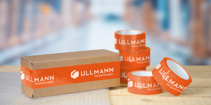 Bedruckte Klebebänder in Großmengen liegen neben einem Karton