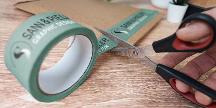Eine Person schneidet ein bedrucktes Klebeband mit einer Schere durch